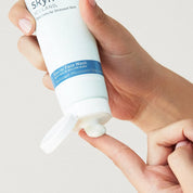 White tube of Glacial Face Wash with blue label held by hand, dispensing cream onto finger.