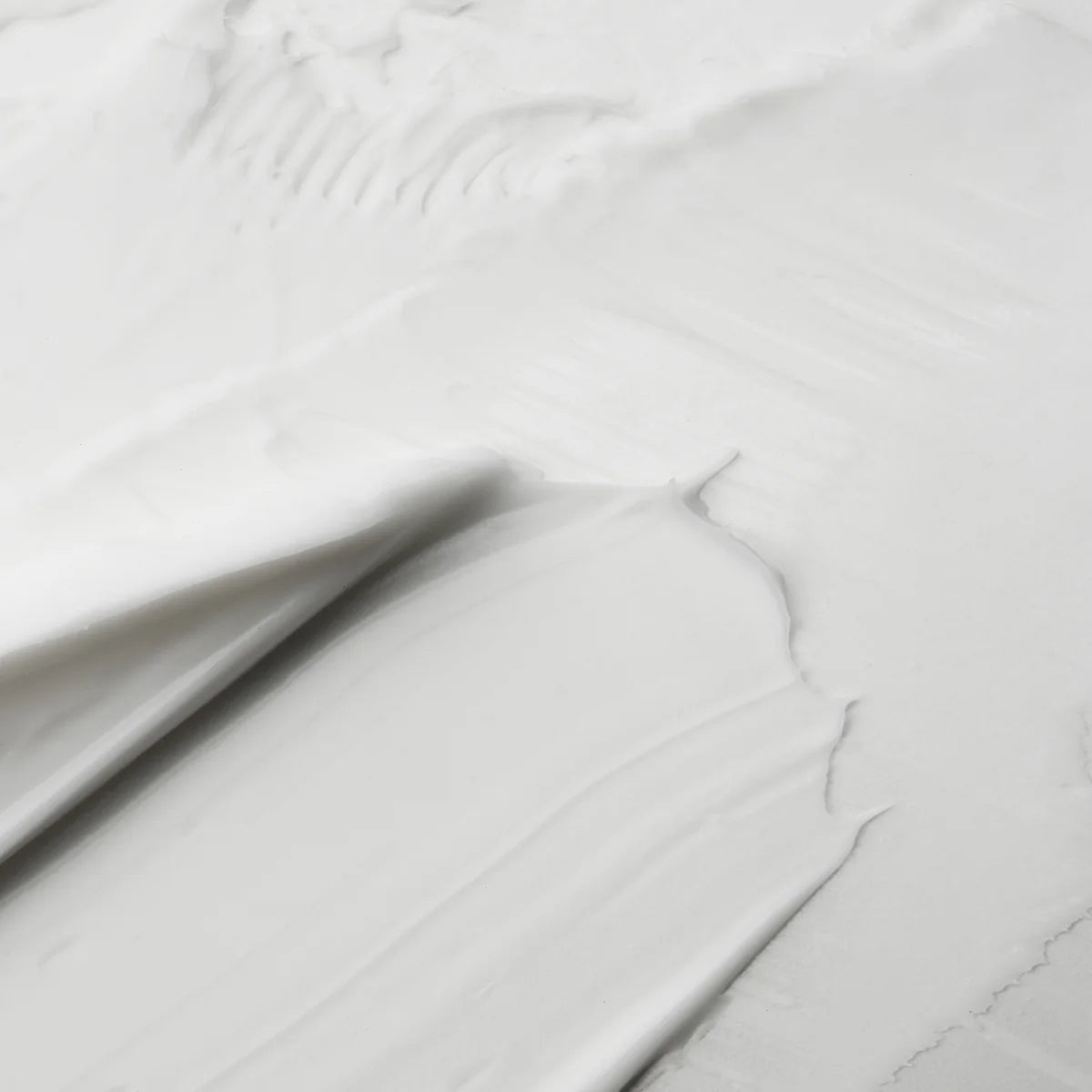 Smooth white cream texture spread in soft swirls on a flat surface.