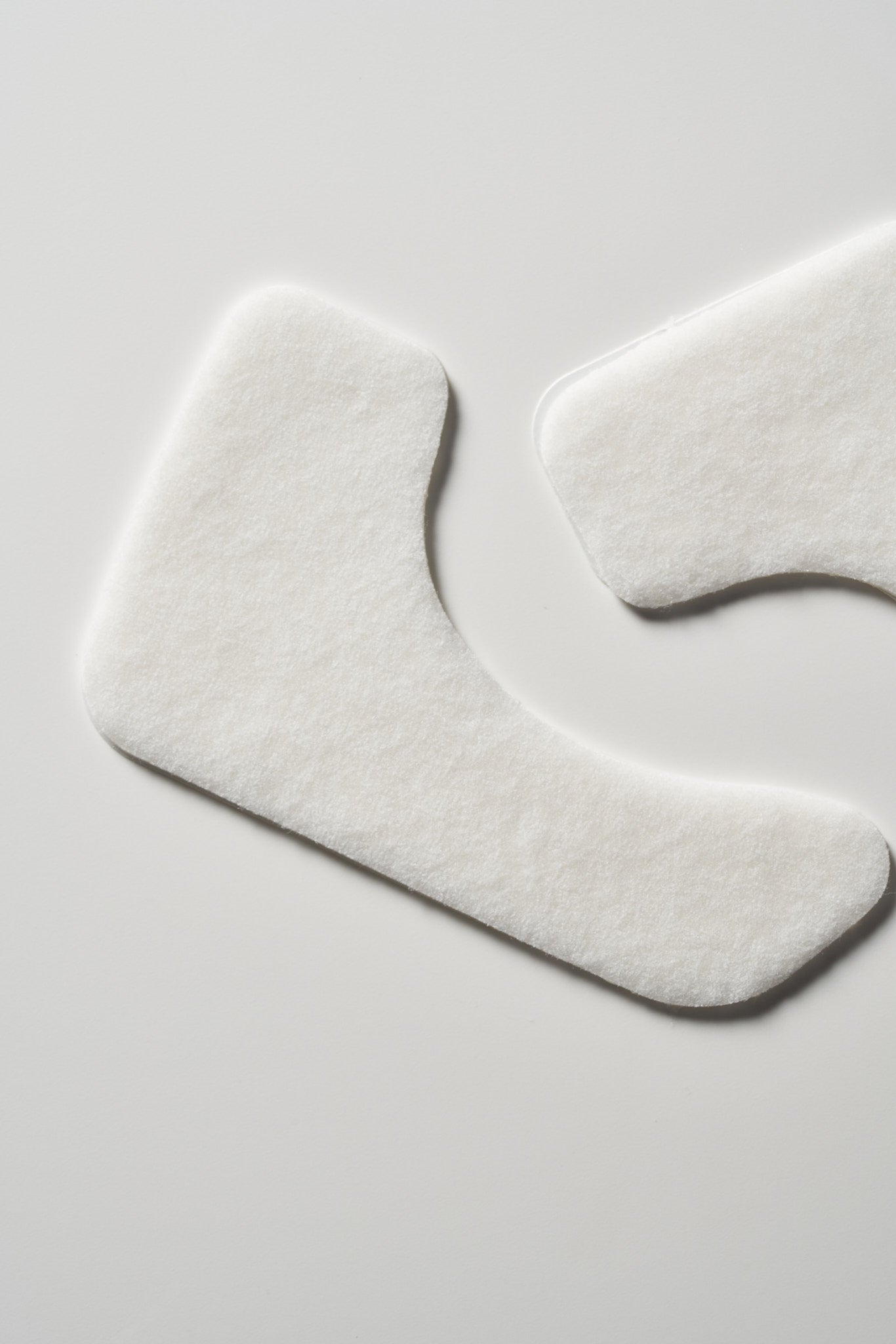 Two white textured Hydro Cool Firming Face Gel patches on a light background, one L-shaped and one irregularly shaped.