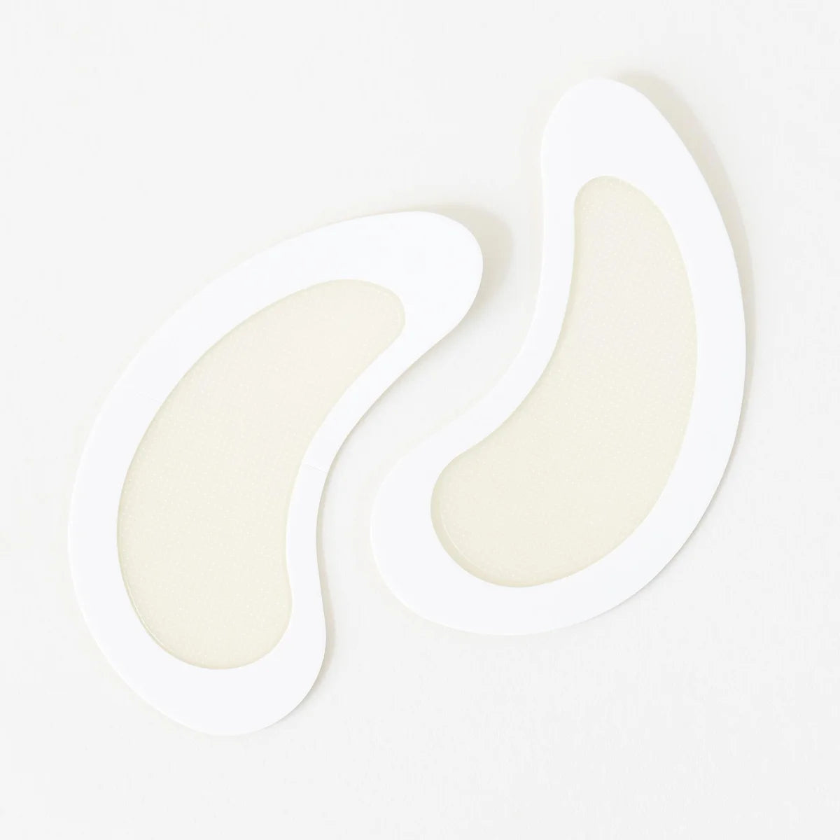 Pair of white, curved dissolving microneedle eye patches with smooth texture.