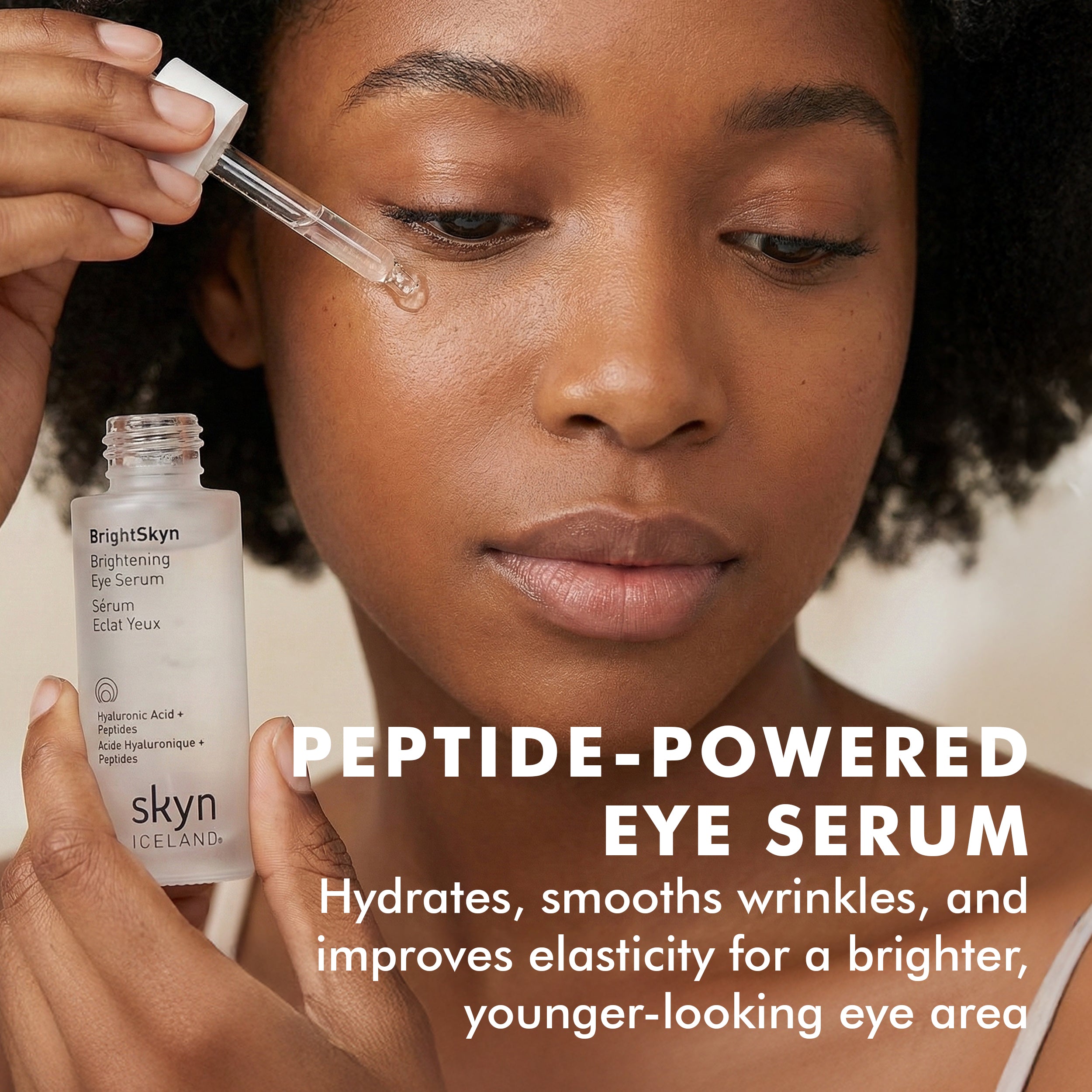 Clear glass dropper bottle with white label reading "Brightening Eye Serum," held near face applying serum under eye.