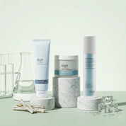 Clear Skin Bundle with three skincare products in white and blue packaging displayed on marble stands with glass labware and .