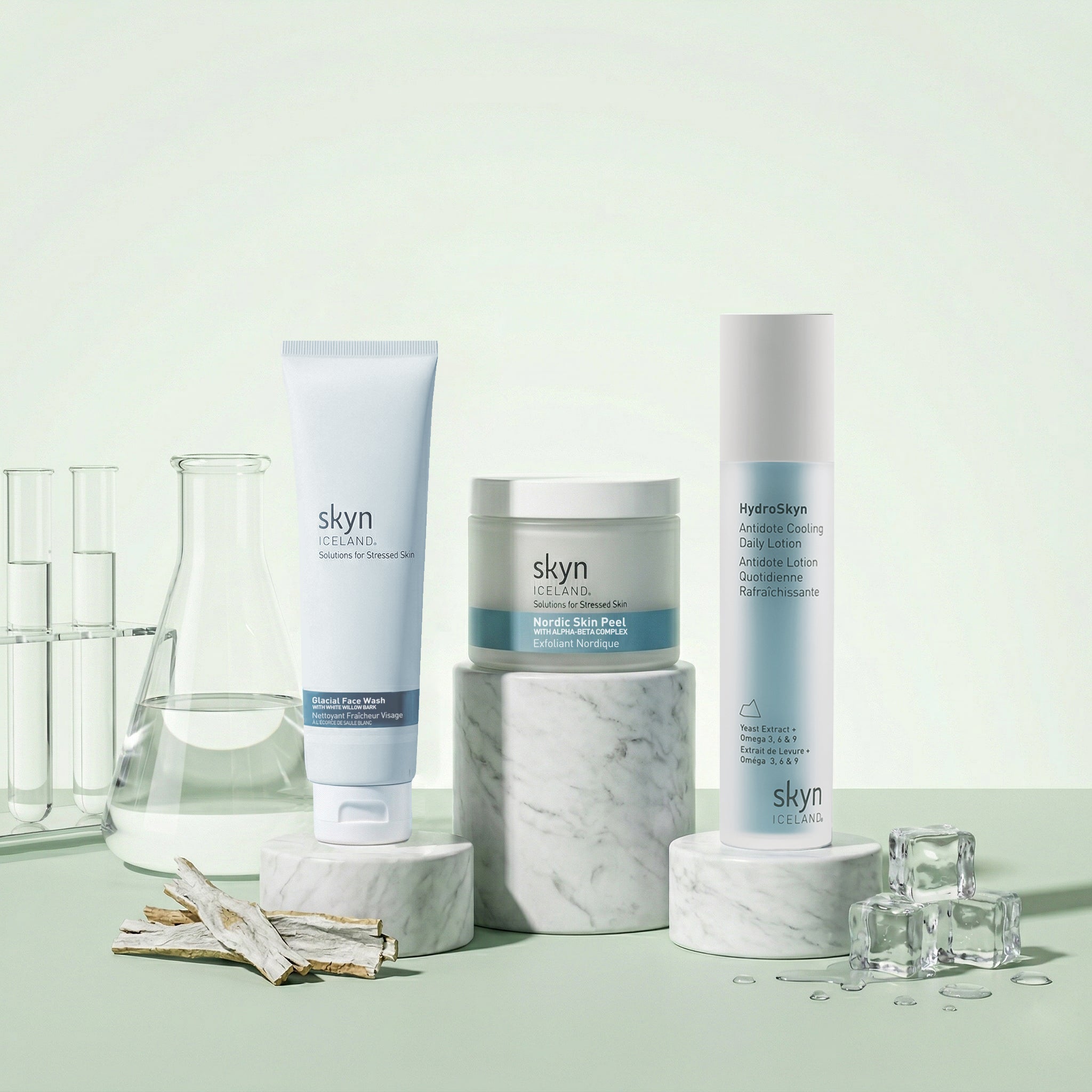 Clear Skin Bundle with three skincare products in white and blue packaging displayed on marble stands with glass labware and .