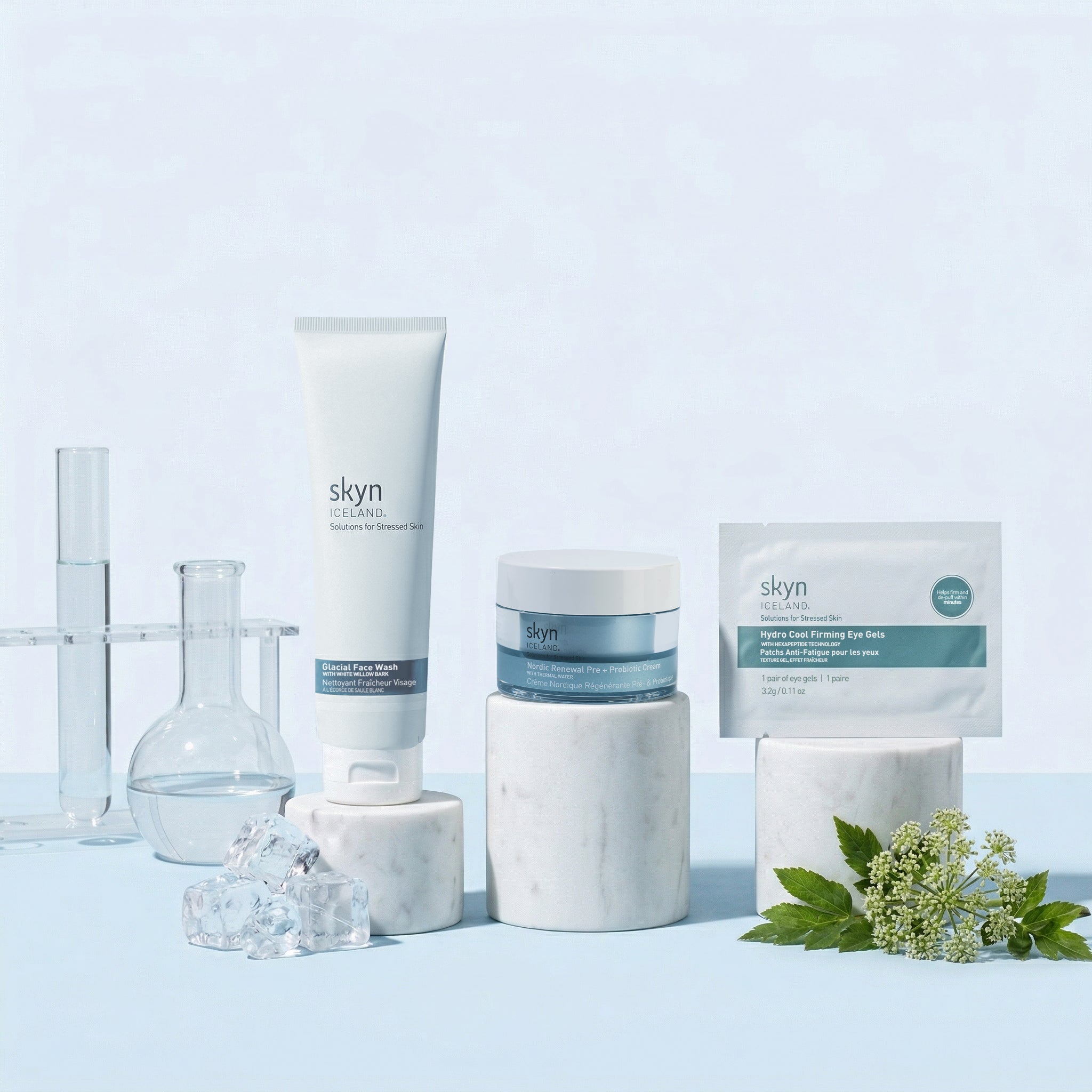 Skyn Iceland Deep Hydration Bundle with white tube, blue jar, soothing gel sachets, and clear glass vessels on white marble.